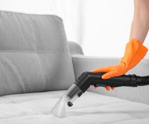 Woman with vacuum cleaner cleaning couch